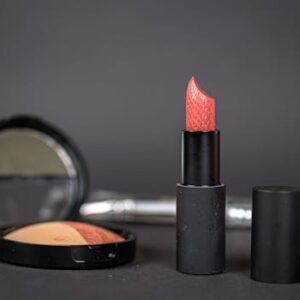 Black lipstick and blush with compact on dark background, showcasing elegant makeup essentials.
