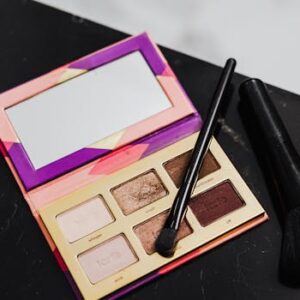 High-angle shot of an eyeshadow palette and makeup brushes on a black marble surface with ample copy space.